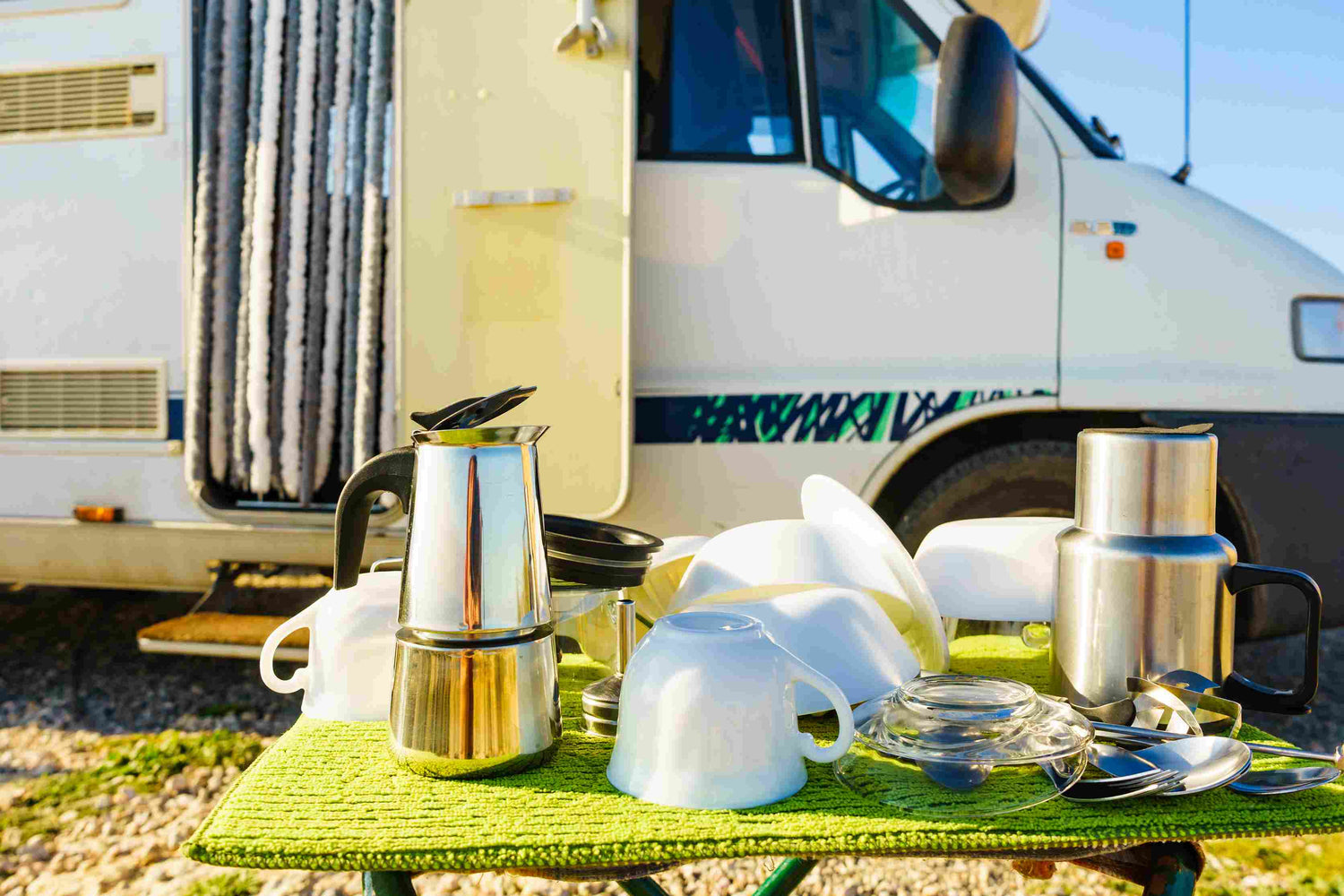 Sauberes Geschirr nach Abwasch, gestapelt auf einem Tisch, im Hintergrund ein Camper